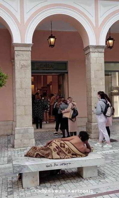 Ημίγυμνος άντρας, καλυμμένος με κουβέρτα, ξάπλωσε μπροστά από εμπορικό κεντρο